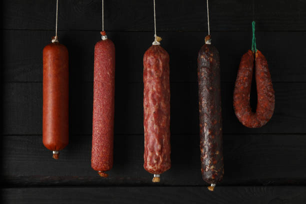 istock Delicious different hanging sausages on wooden background 1199954008