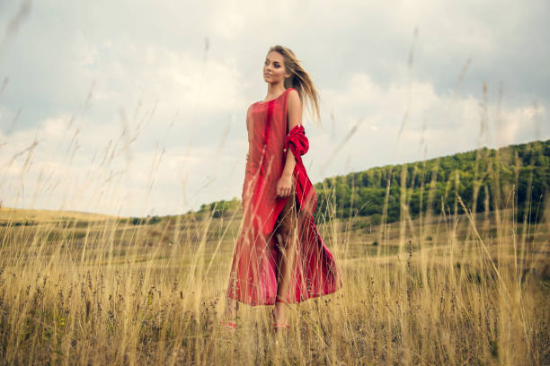 istock Beautiful young blonde enjoys walking through grass in summer 1199954347