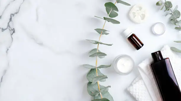 Herbal bodycare cosmetic hygienic cream, lotion, essential oil, towel and eucalyptus leaves. Organic beauty products. Flat lay, top view, copy space. Spa cosmetic products concept