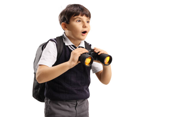 Schoolboy holding binoculars and looking in distance Schoolboy holding binoculars and looking in distance isolated on white background elementary student pointing stock pictures, royalty-free photos & images