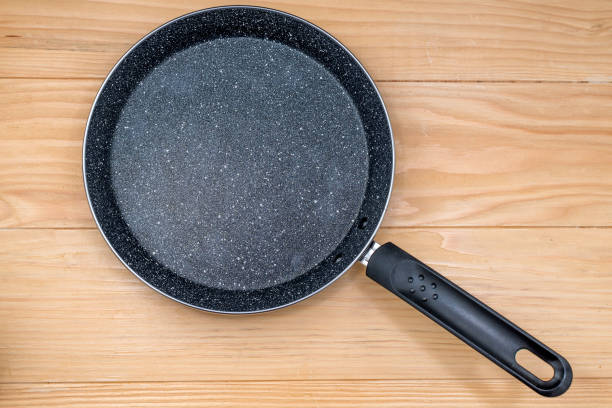 istock Cast-iron frying pan isolated on a wooden background. 1199960591