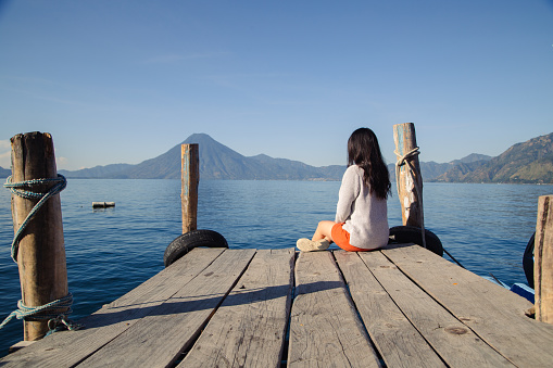 Hispanic tourist sitting on the pier of Lake Atitlan, Guatemala, man from behind