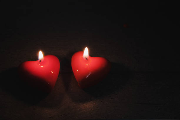 istock Two heart shaped candles burn in the darkness, copy space. 1199961622