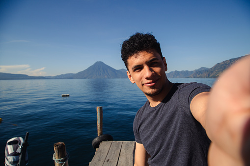 Hispanic traveler taking a selfie at Lake Atitlan in Guatemala at sunrise