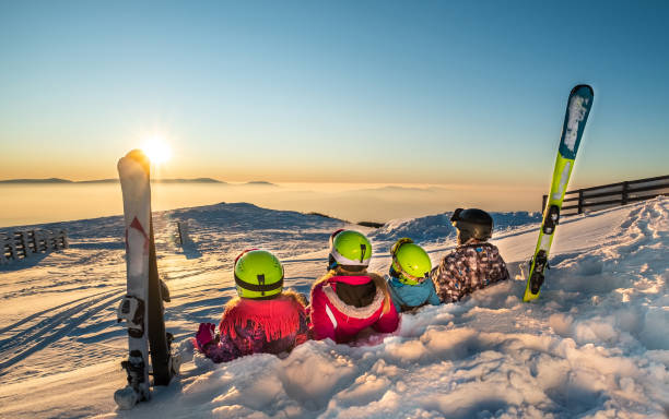 Family on ski vacation Happy family is lying on snow and watching on sunset from top of the mountain skiing stock pictures, royalty-free photos & images