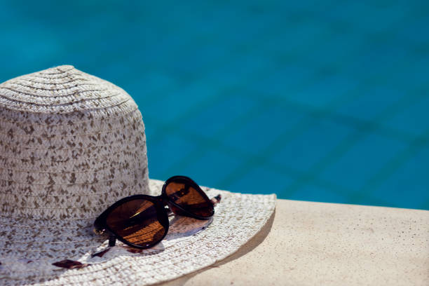 istock Hat and sunglasses lying beside pool. Summer and holiday concept 1199961965