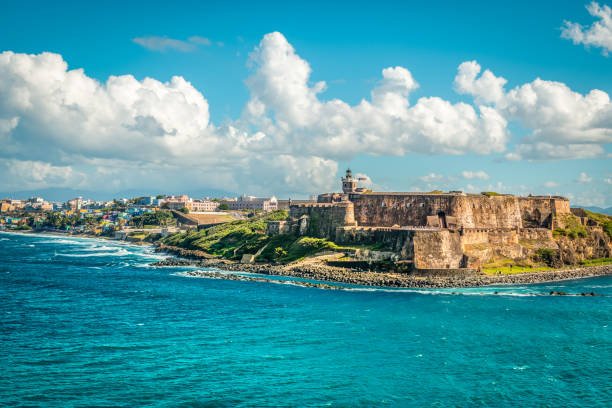 Landscape with Castillo San Felipe del Morro, a top attraction in San Juan, capital city of Puerto Rico. Travel image with historical fort along the coastline at the seaport of San Juan in Puerto Rico. White clouds against blue sky, blue sea and old castle. san juan stock pictures, royalty-free photos & images