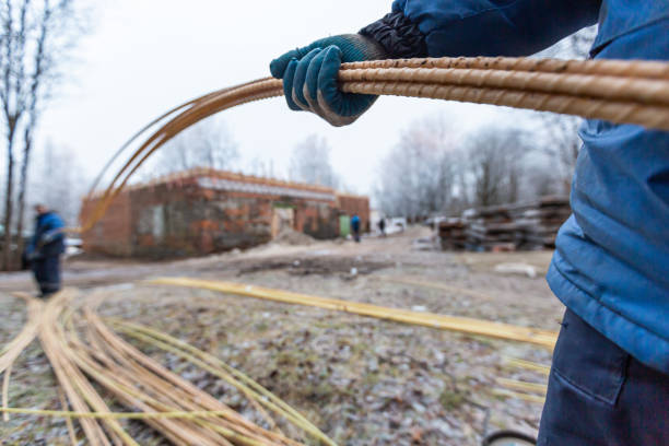 istock Workers in protect gloves are holding light polymer reinforcement in construction site. Concept of using of light construction materials during  construction, remodeling, renovation, extension, overhaul, restoration and reconstruction. 1199963316