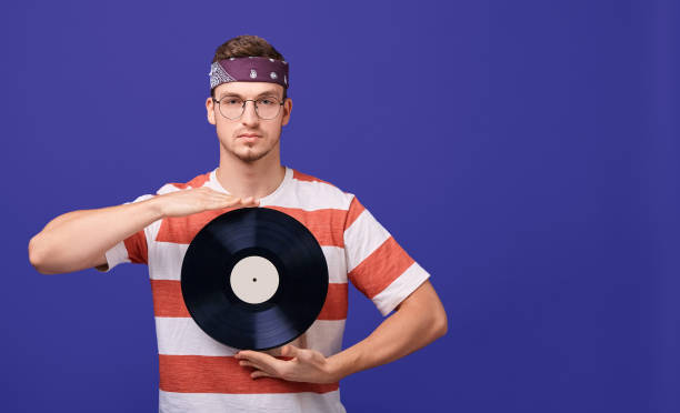 istock Cute guy in glasses holds a music record in his hands. 1199964132