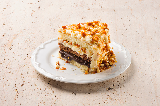 Slice of a delicious three layered cake, with chocolate and white chocolate filling and white chocolate and nuts topping