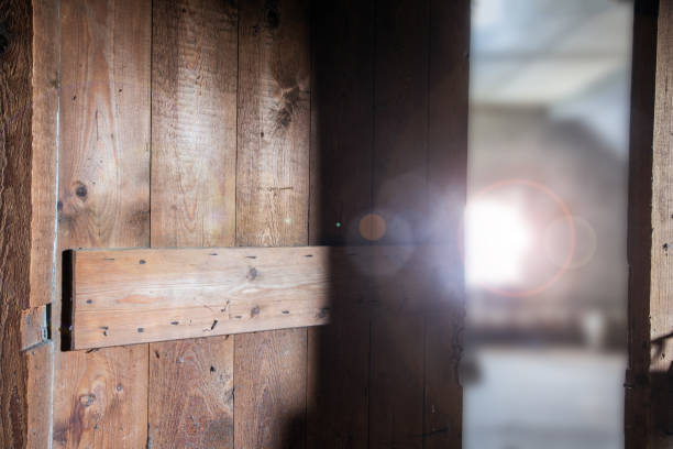 Old wooden dark abandoned attic with sunlight through the window and a open door, needs renovation close-up
