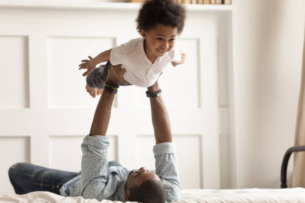 istock Cute funny black boy flying in strong fathers hands. 1199968713