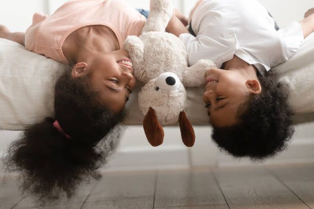 istock Happy black brother and sister laying upside down on bed. 1199968719