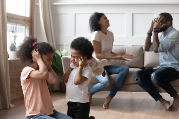 Little black kids suffering from parents emotional quarrel. Two african american upset stressed children close ears, suffering from negative emotions, blurred parents shouting, arguing with each other on background, family problem, break up, divorce concept. man closing ears photos stock pictures, royalty-free photos & images