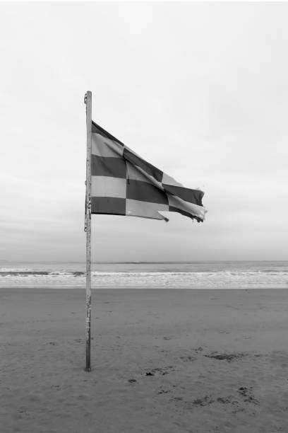 istock Waving old flag on the empty beach. Black and white photo 1199972318