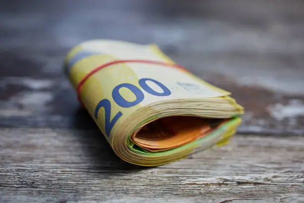 bundle of 200 Euro banknotes bound with household rubber on wooden surface
