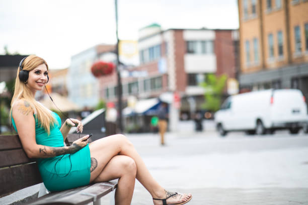 Beautiful young blond caucasian woman listening to podcast on her smartphone.