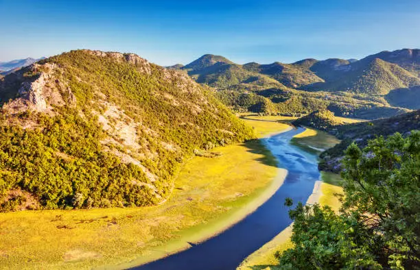 Sinuous river flowing through mountains. Natural park. Dramatic scene. Rijeka Crnojevica. Located near Skadar Lake, Montenegro, Europe. Beauty world.