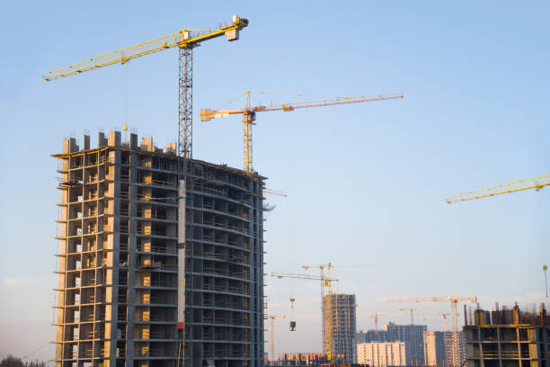 istock Tower cranes constructing a new residential building at a construction site against blue sky. Renovation program, development, concept of the buildings industry. 1199982812