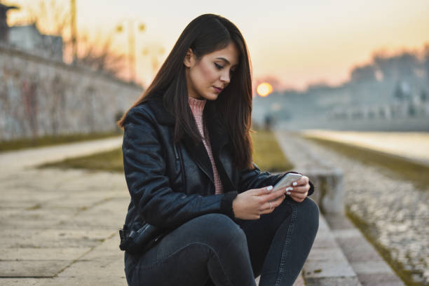 istock Beautiful young woman using smartphone 1199987521