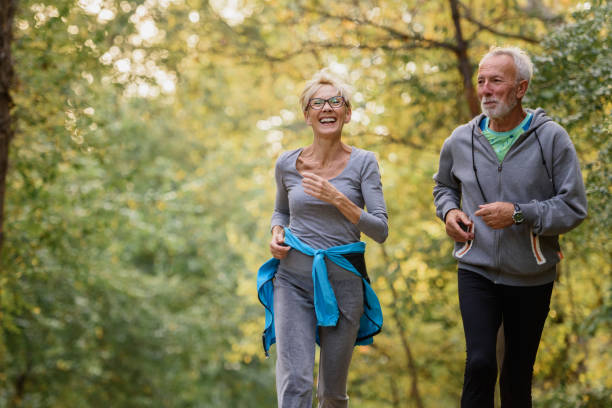 Cheerful active senior couple jogging in the park in the morning Cheerful active senior couple jogging in the park. Exercise together to stop aging. active seniors stock pictures, royalty-free photos & images