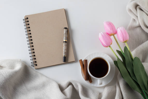 istock Notebook, cup of hot coffee, scarf, tulips on white background. Spring Concept. Flat lay, top view 1199988905