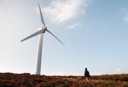 A woman hiker walks towards a wind farm in British countryside