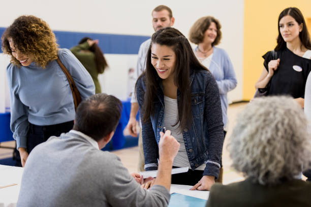 istock Young woman smiles as she interacts with voting volunteer 1199991208