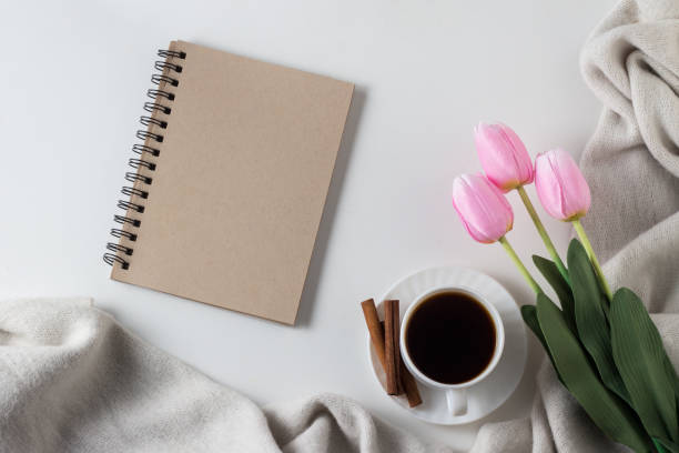 istock Notebook, cup of hot coffee, scarf, tulips on white background. Spring Concept. Flat lay, top view 1199992168