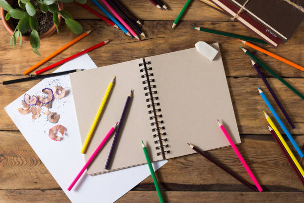 istock Open Notepad, Pure Paper Sheet, Colored Pencils on the Old Wooden Table. Flat lay, top view 1199992183