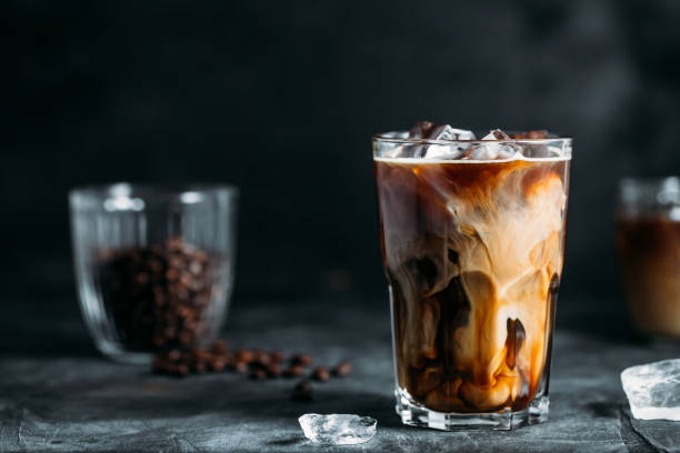 istock Milk Being Poured Into Iced Coffee on a dark table 1199993344