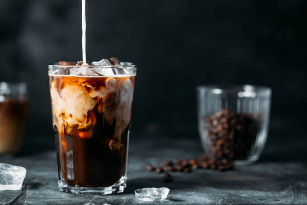 istock Milk Being Poured Into Iced Coffee on a dark table 1199993351