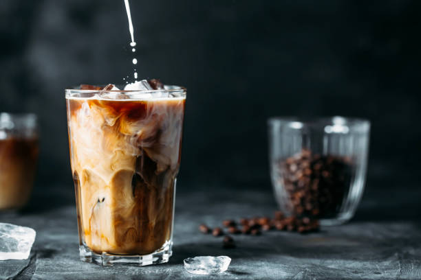 milk being poured into iced coffee on a dark table - pouring coffee liquid coffee bean imagens e fotografias de stock