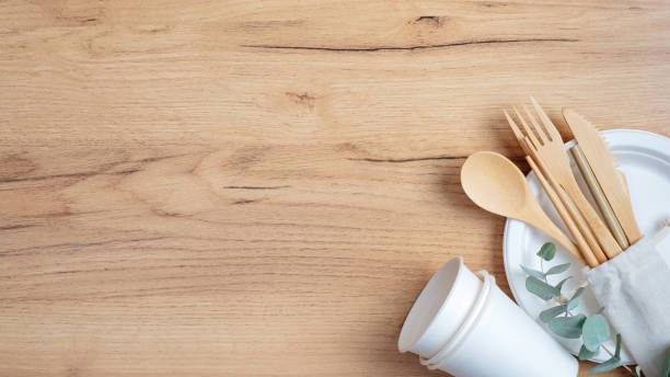 istock Reusable eco natural bamboo utensils cutlery with biodegradable paper cups and plate on wooden table. Top view, flat lay, copy space. Zero waste, plastic free concept. Sustainable lifestyle 1200002310
