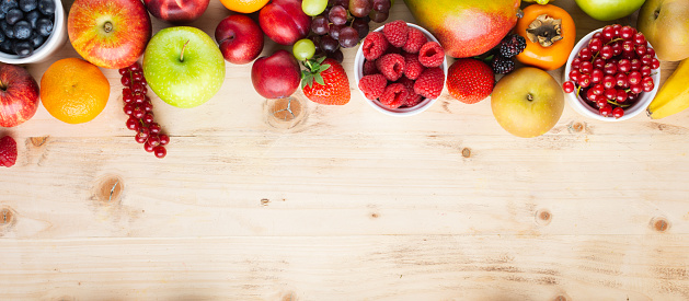 Banner, healthy fruits berries background, strawberries raspberries oranges plums apples grapes blueberries mango persimmon on wooden table, top view, copy space for text, selective focus