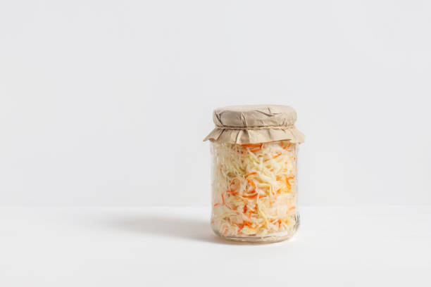 homemade sauerkraut. fermented food. sauerkraut with carrots in a glass jar on a white wooden background - bigos imagens e fotografias de stock