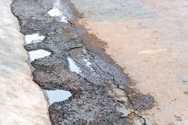 istock Dirty damaged asphalt road with water filled potholes. 1200021503
