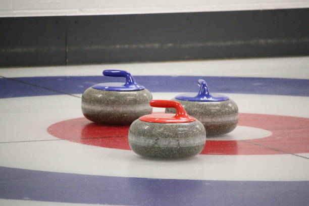 istock Three curling stones near the button on a curling rink 1200022602