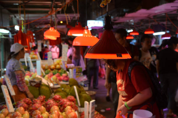 People buying fruit at a street market in Mongkok district by night, Kowloon Peninsula.  The area, with its extremely high population density of 130,000/km2 was described as the busiest district in the world. Hong Kong