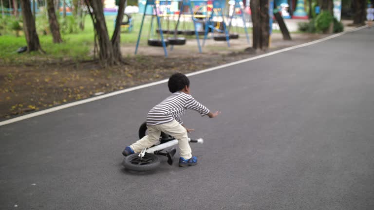 Asian little Boy Learn to ride and falling a bicycle in public park