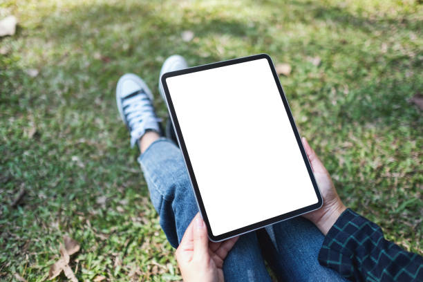istock a woman holding and using black tablet pc with blank white desktop screen while sitting in the outdoors 1200033461
