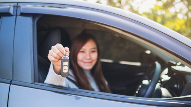 woman holding car key while sitting in the car