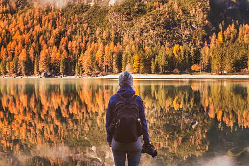 travel in autumn outdoors, photographer traveler with backpack and dslr camera standing near mountain lake