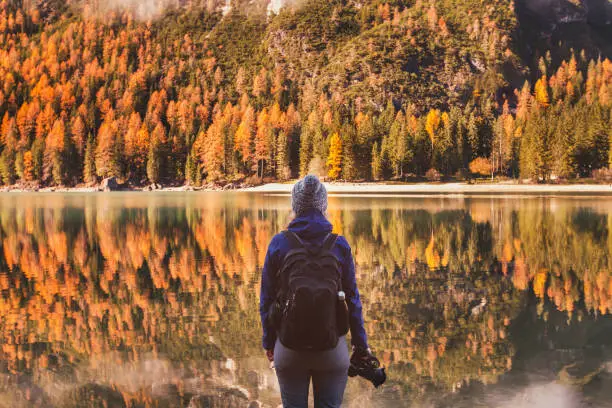 Photo of travel in autumn outdoors, photographer traveler with backpack and dslr camera