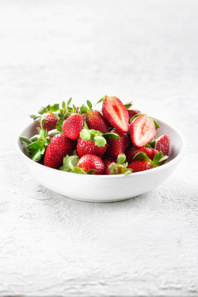istock Heap of fresh strawberries in ceramic bowl on white background 1200043304