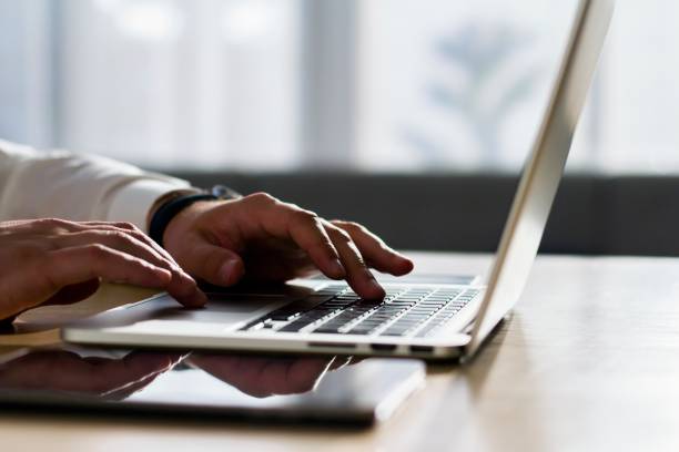 istock A man in a white shirt working with laptop, close up 1200048658