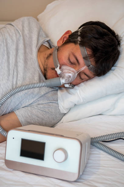 istock Healthy young man wearing ( CPAP Mask ) nasal mask and using CPAP machine for sleeping smoothly all night 1200053388