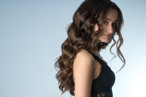 beautiful girl with long curly hair in studio on grey background