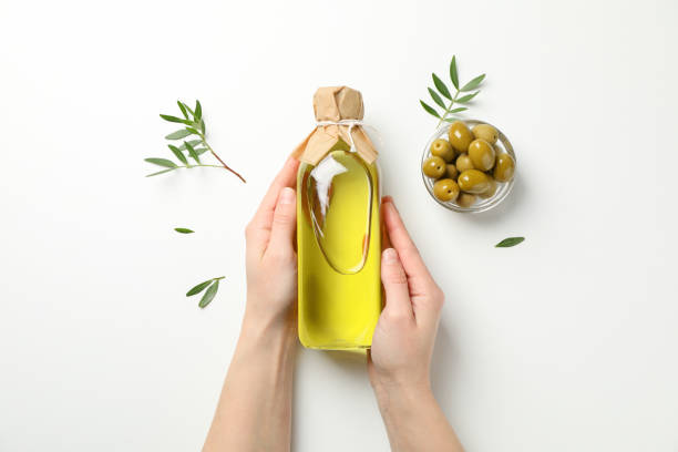 istock Female hands hold bottle with olive oil on white background, top view 1200062229