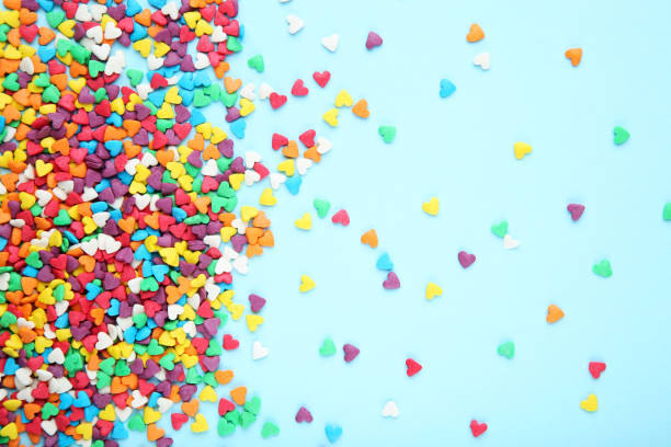 istock Colorful heart shaped sprinkles on blue background 1200062468